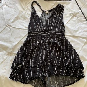 Low cut black romper. White flower detailing.